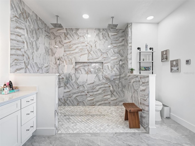 bathroom with tiled shower, vanity, and toilet