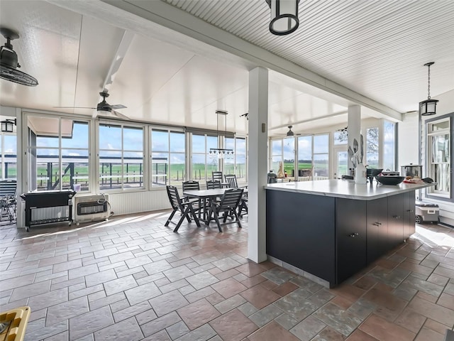 sunroom with beamed ceiling, ceiling fan, and heating unit