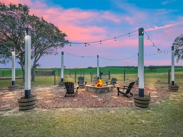 playground at dusk featuring a rural view, a lawn, and an outdoor fire pit