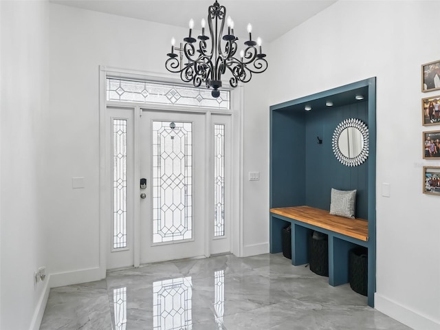 foyer entrance with baseboards, marble finish floor, and a chandelier