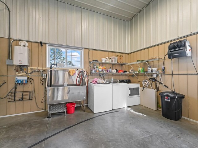 garage featuring independent washer and dryer, tankless water heater, and a sink