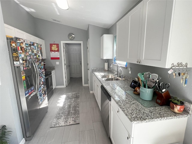 kitchen with stainless steel appliances, white cabinetry, light stone countertops, and sink