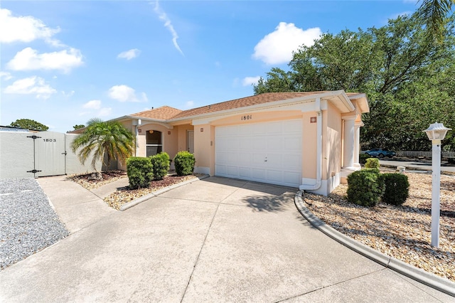 view of front of home featuring a garage, stucco siding, concrete driveway, and a gate