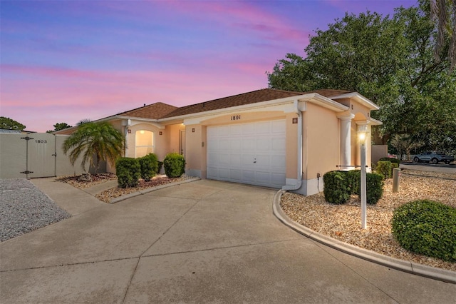 view of front of home with driveway, a gate, a garage, and stucco siding