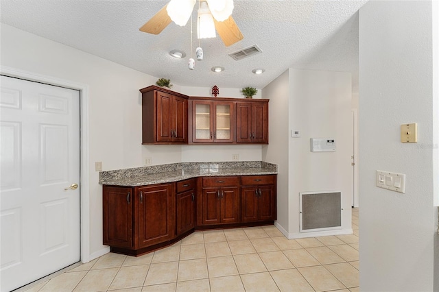 kitchen with light stone counters, light tile patterned floors, dark brown cabinets, and visible vents