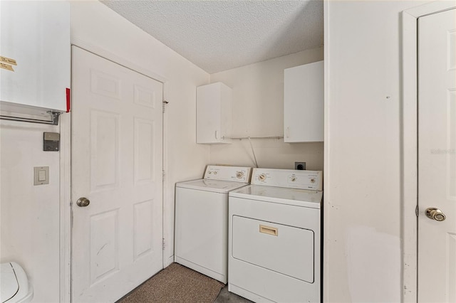 laundry area with washer and dryer, a textured ceiling, and cabinet space