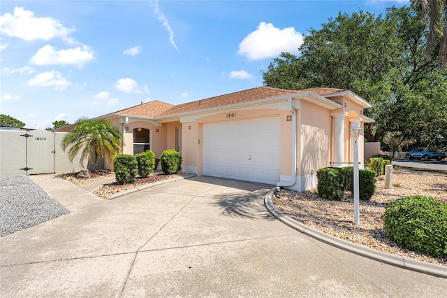 view of front of home featuring an attached garage, concrete driveway, stucco siding, and a gate