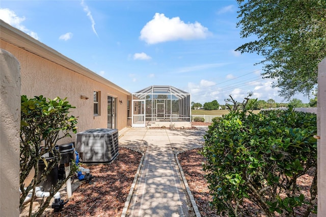 view of yard featuring central air condition unit, a patio area, fence, and glass enclosure