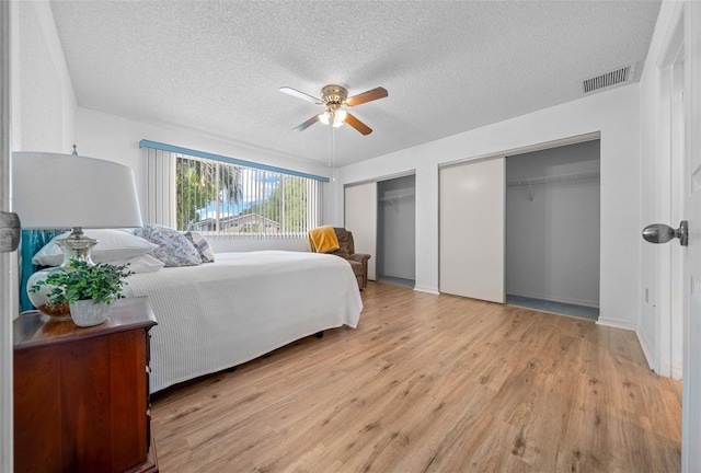 8450 SW 115th Street Rd, Ocala, FL 34481 - bedroom with light wood finished floors, a textured ceiling, visible vents, two closets, and ceiling fan