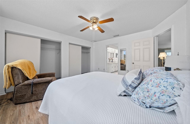 8450 SW 115th Street Rd, Ocala, FL 34481 - bedroom featuring a textured ceiling, visible vents, two closets, ceiling fan, and wood finished floors