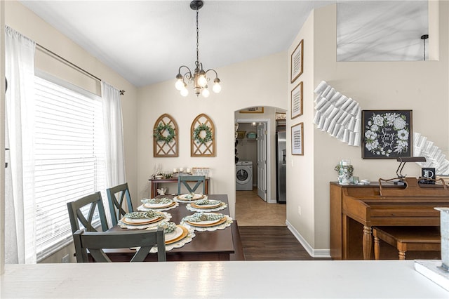 dining area featuring dark wood-type flooring, washer / dryer, and a notable chandelier