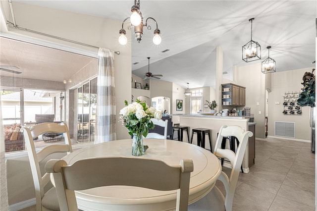 dining space featuring light tile patterned flooring, lofted ceiling, and ceiling fan with notable chandelier