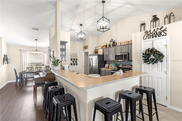 kitchen featuring an inviting chandelier, hanging light fixtures, a kitchen breakfast bar, and appliances with stainless steel finishes