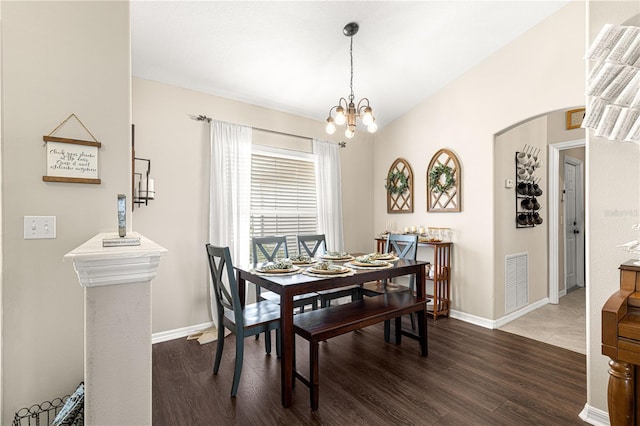 dining space with lofted ceiling, a notable chandelier, and dark wood-type flooring