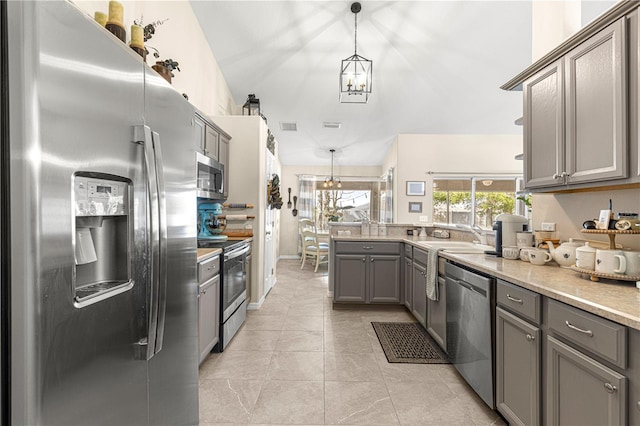 kitchen featuring pendant lighting, sink, gray cabinetry, stainless steel appliances, and a chandelier