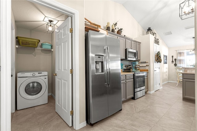 kitchen with stainless steel appliances, vaulted ceiling, washer / dryer, and gray cabinets