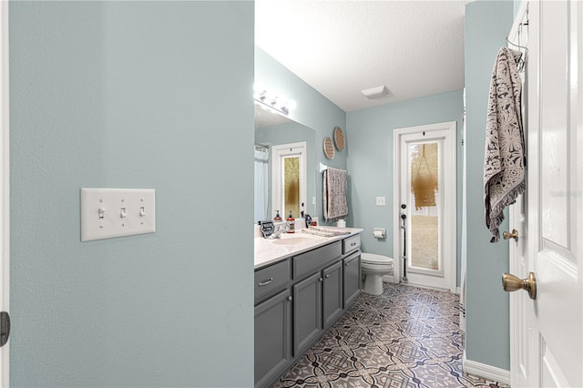 bathroom featuring vanity, toilet, tile patterned flooring, and a textured ceiling