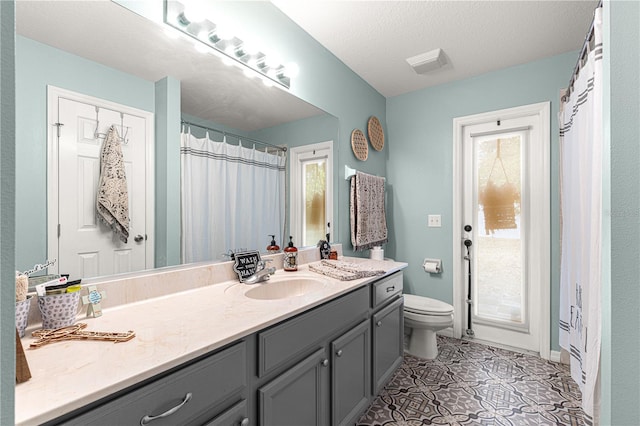 bathroom with vanity, toilet, tile patterned flooring, and a textured ceiling