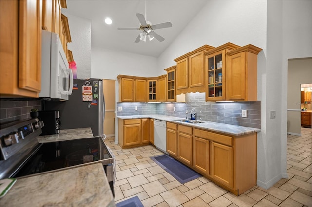 kitchen with sink, ceiling fan, stainless steel appliances, high vaulted ceiling, and tasteful backsplash