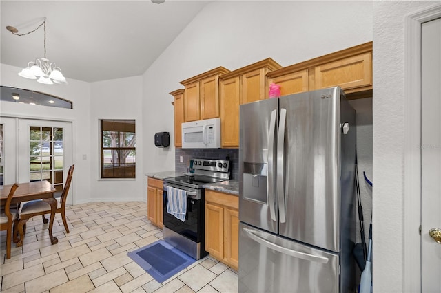 kitchen featuring vaulted ceiling, pendant lighting, tasteful backsplash, a chandelier, and stainless steel appliances