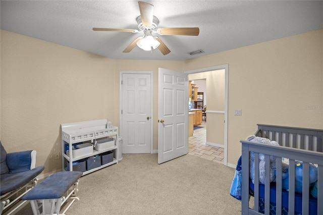 bedroom with ceiling fan, light carpet, and a textured ceiling