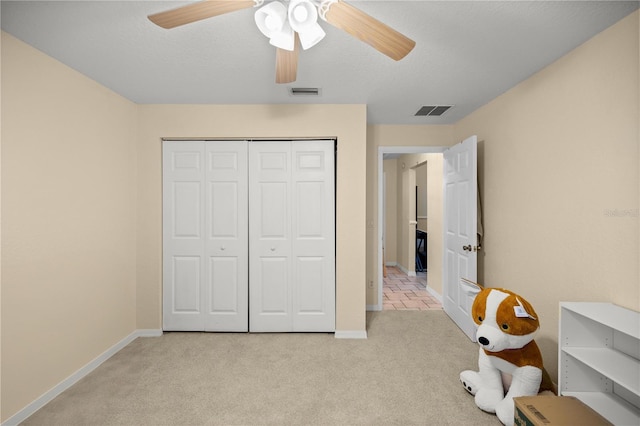 carpeted bedroom featuring a textured ceiling, a closet, and ceiling fan