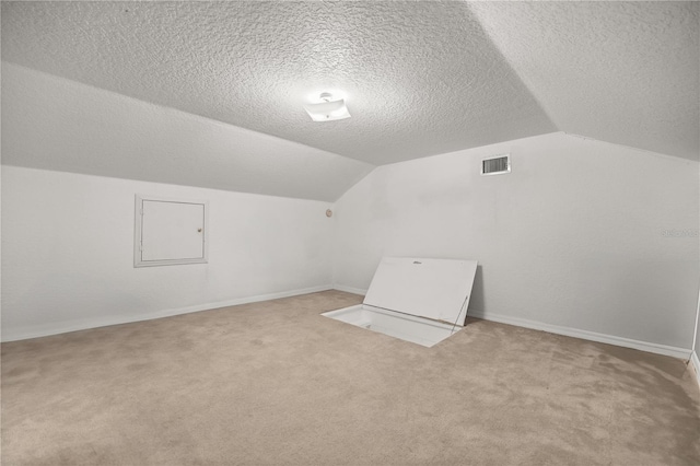 bonus room with vaulted ceiling, a textured ceiling, and carpet flooring