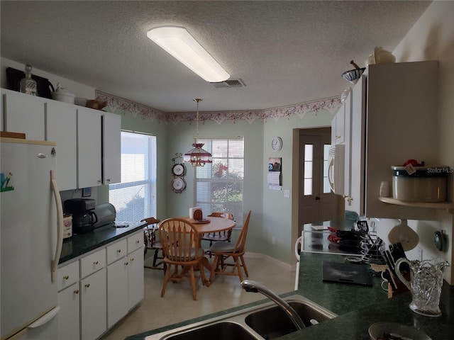 kitchen with sink, a textured ceiling, hanging light fixtures, white appliances, and white cabinets