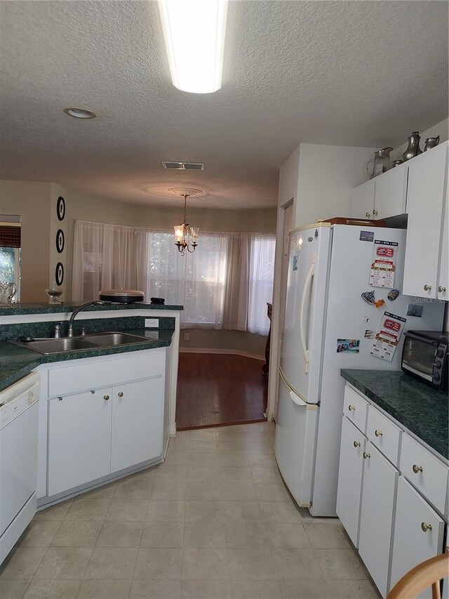 kitchen with sink, white appliances, a notable chandelier, white cabinets, and decorative light fixtures