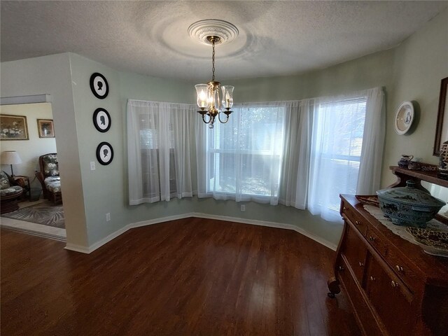 dining room with dark wood-type flooring, a chandelier, and a textured ceiling