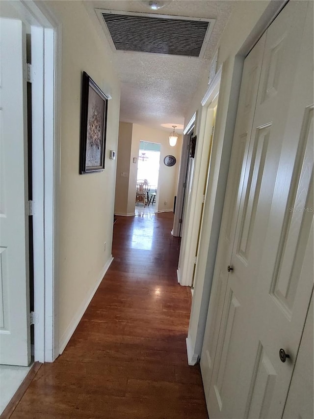 hall featuring dark wood-type flooring and a textured ceiling