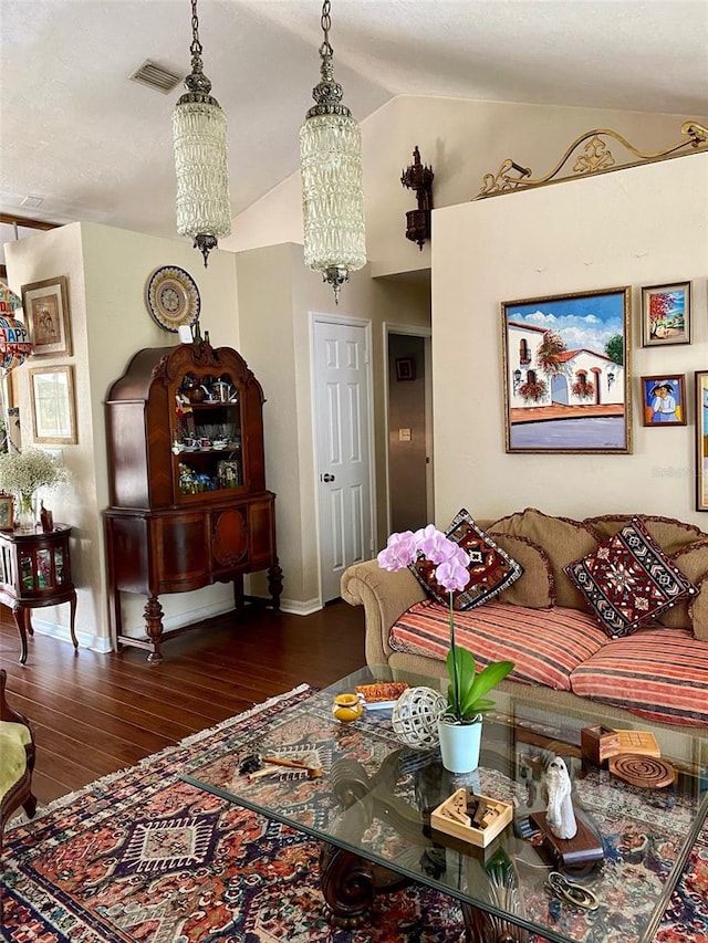 living area with vaulted ceiling, hardwood / wood-style floors, visible vents, and baseboards