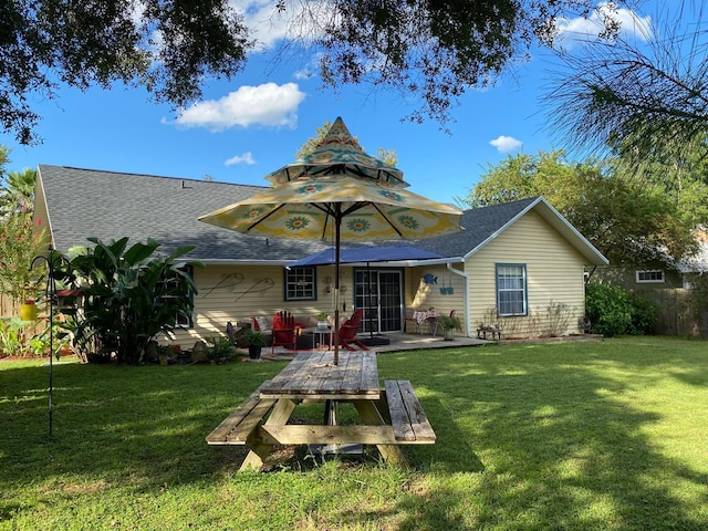 back of house featuring roof with shingles, a yard, and a wooden deck