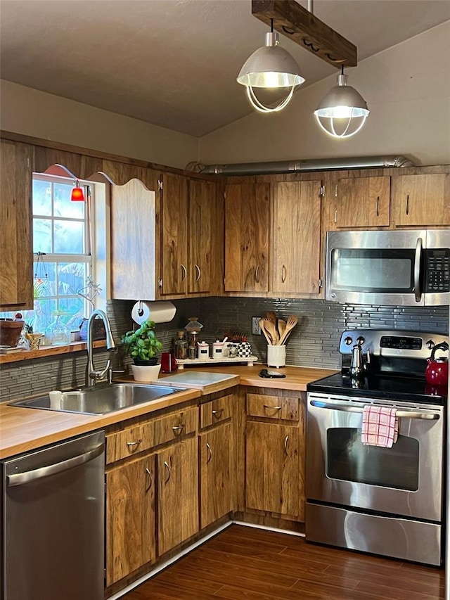 kitchen featuring tasteful backsplash, dark wood finished floors, appliances with stainless steel finishes, vaulted ceiling, and a sink