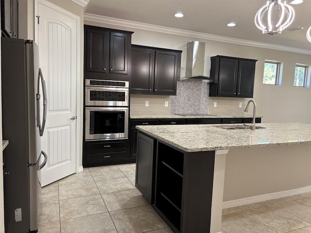 kitchen featuring pendant lighting, sink, crown molding, stainless steel appliances, and wall chimney exhaust hood