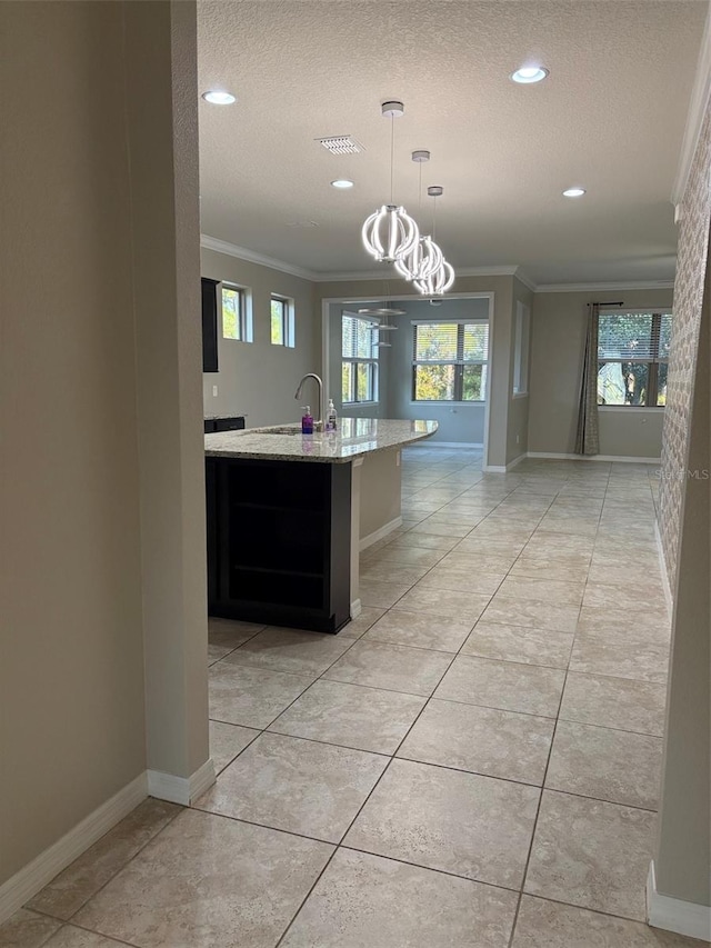 kitchen featuring light tile patterned floors, crown molding, hanging light fixtures, light stone counters, and a textured ceiling