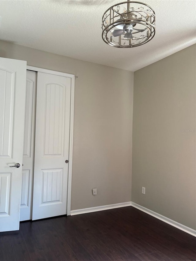 unfurnished bedroom with dark wood-type flooring, a textured ceiling, and a closet