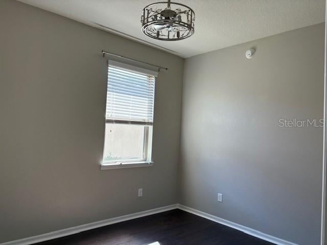 spare room with dark wood-type flooring and a textured ceiling