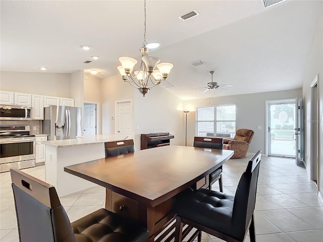 tiled dining area with lofted ceiling and ceiling fan with notable chandelier