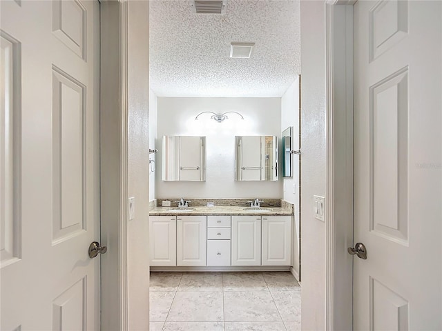 bathroom featuring tile patterned flooring, vanity, and a textured ceiling