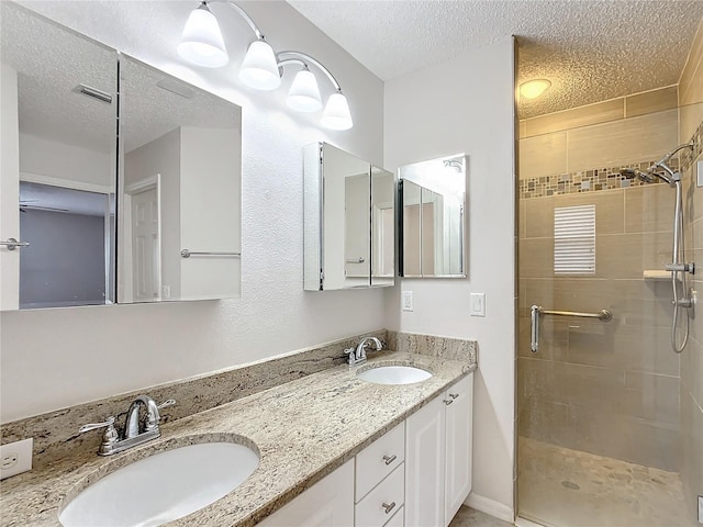 bathroom with vanity, a shower with door, and a textured ceiling