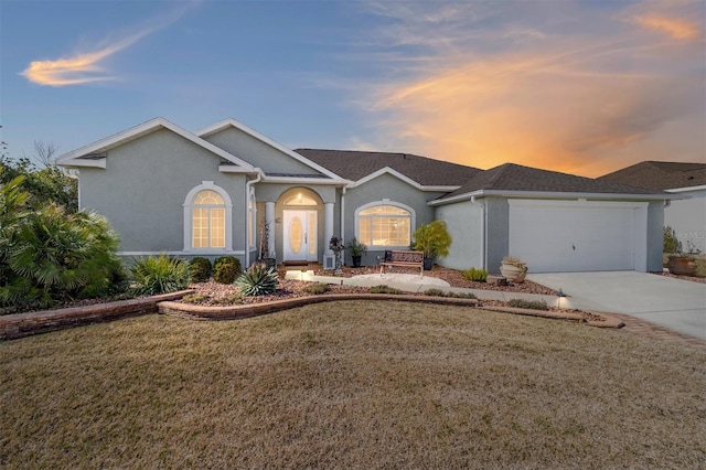 ranch-style home with a garage and a yard