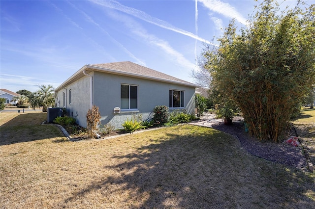 view of side of property featuring cooling unit and a yard