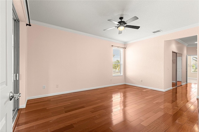 spare room with crown molding, plenty of natural light, and hardwood / wood-style floors