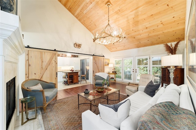 living room featuring an inviting chandelier, high vaulted ceiling, light wood-type flooring, wooden ceiling, and a barn door