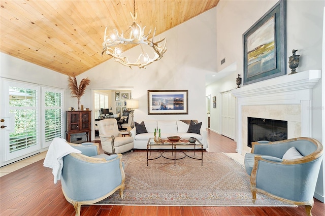 living room with hardwood / wood-style floors, wood ceiling, a tile fireplace, and a chandelier