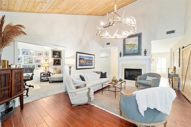 living room with high vaulted ceiling, wood-type flooring, a chandelier, a tiled fireplace, and wooden ceiling