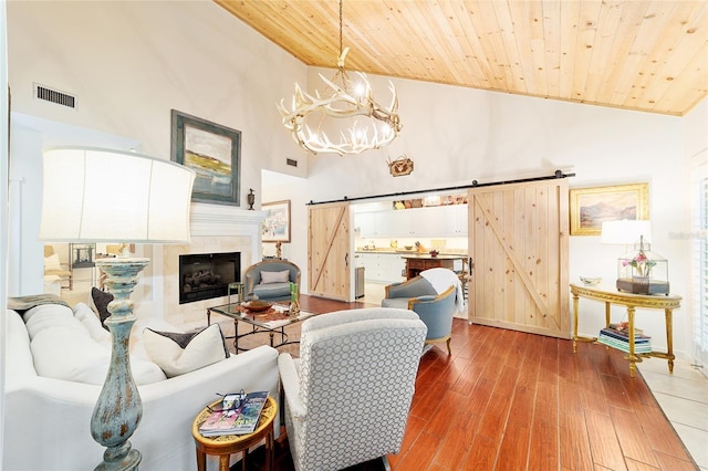 living room featuring wood ceiling, a barn door, high vaulted ceiling, and hardwood / wood-style flooring