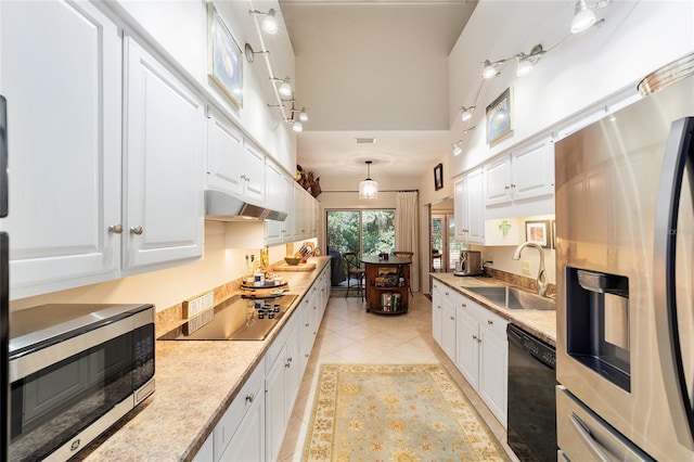 kitchen with a towering ceiling, pendant lighting, white cabinetry, sink, and black appliances