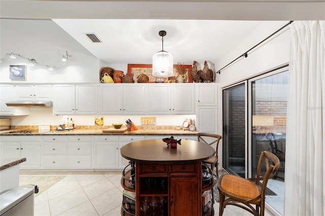 kitchen with lofted ceiling, decorative light fixtures, light tile patterned floors, black electric stovetop, and white cabinets